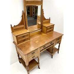Edwardian ash dressing table, raised mirror back with dentil frieze, nine drawers, turned supports on castors 