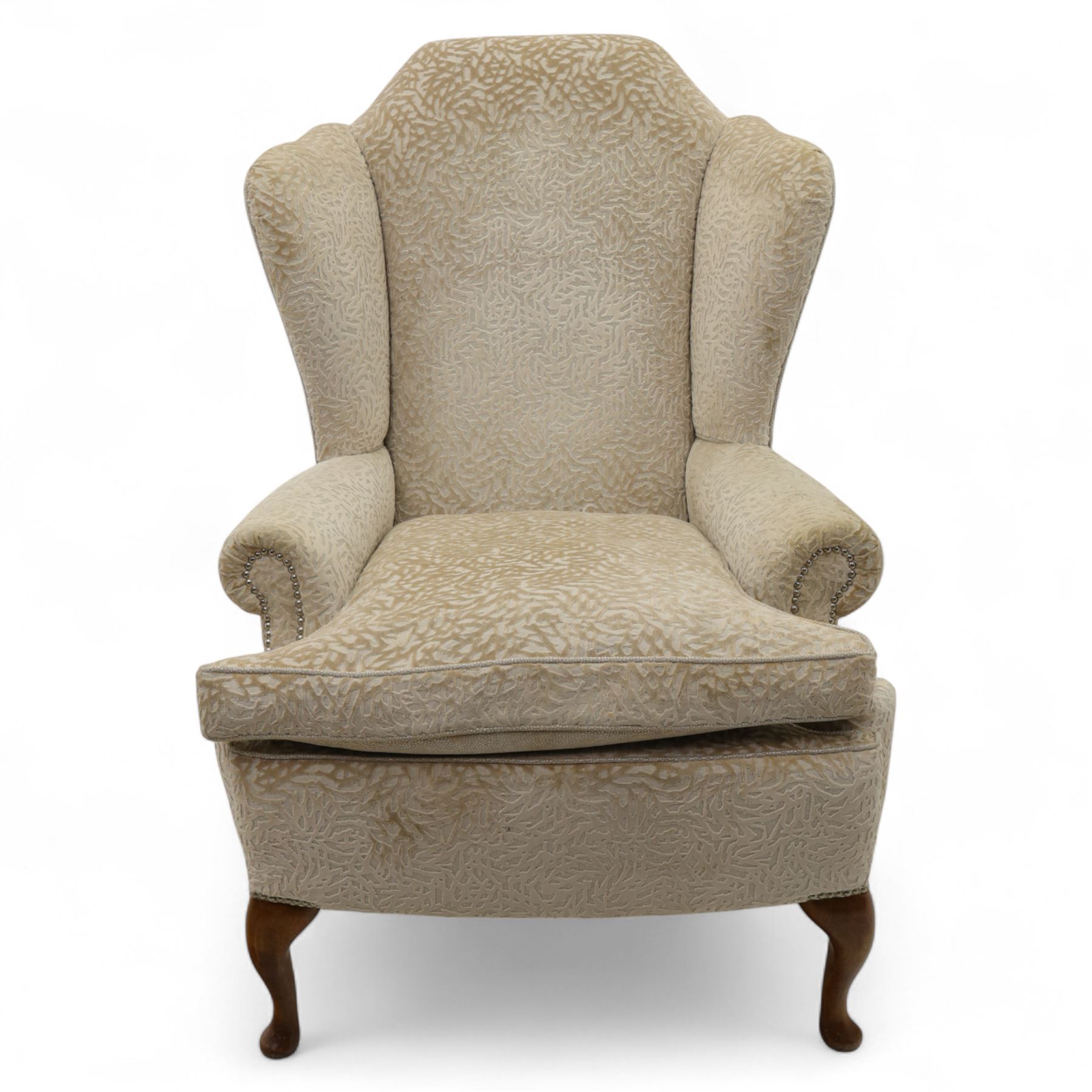 Late 20th century wingback armchair, upholstered in beige embossed fabric with brass stud edging, on cabriole legs and splayed rear legs
