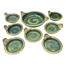 Studio pottery terracotta dishes, comprising large serving dish and seven smaller dishes, each with moulded fish to rim, upon a blue green glaze by Josie Walter, signed beneath, largest D31cm