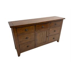 Stained pine rustic sideboard, rectangular top over seven drawers and single panelled cupboard, fitted with shell handles