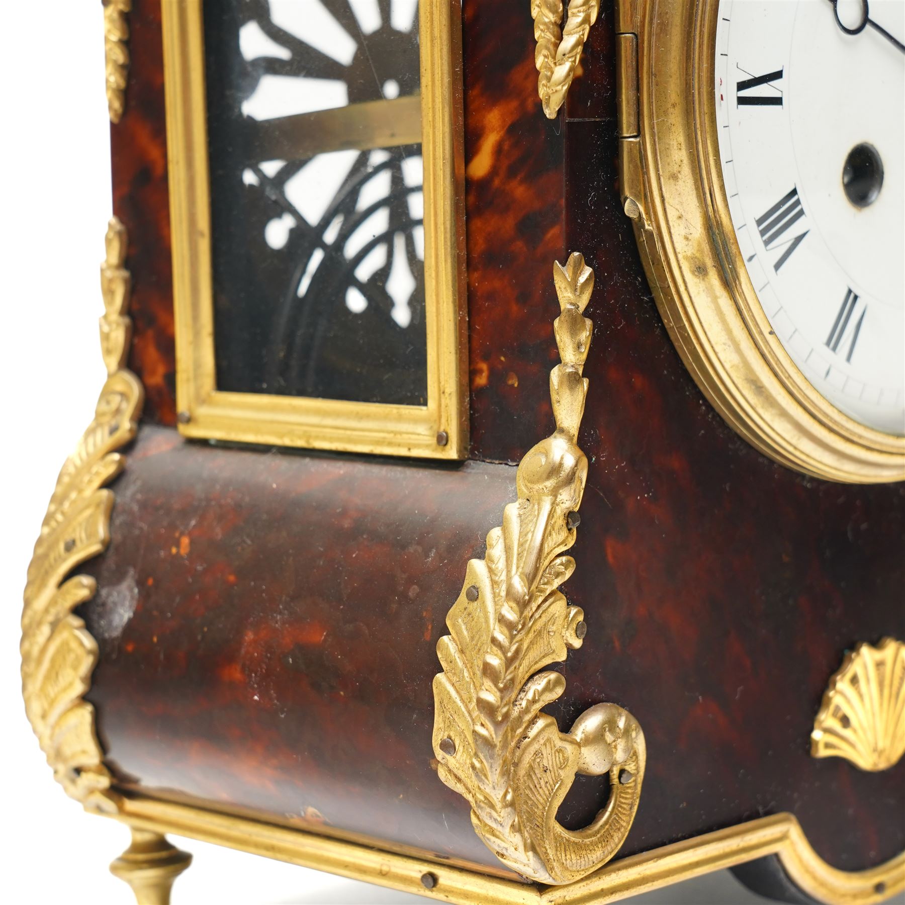 French-late 19th century brown stained 8-day faux Tortoise shell and ormolu mounted mantle clock, rectangular case with glazed side panels and shaped pediment with matching finials, convex enamel dial with Roman numerals, minute track and steel moon hands within a cast brass glazed dial bezel,
twin barrel movement with rack striking, striking the hours and half hour on a coiled gong. With pendulum and key.