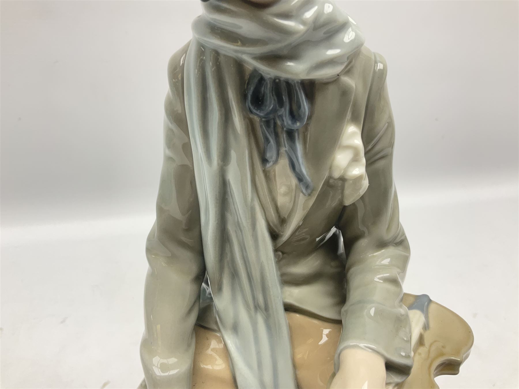 Lladro figure, Violinist, modelled as a man seated upon a  mile stone holding a violin, sculpted by Salvador Furió, no 4887,  year issued 1984, year retired 1981, H35cm