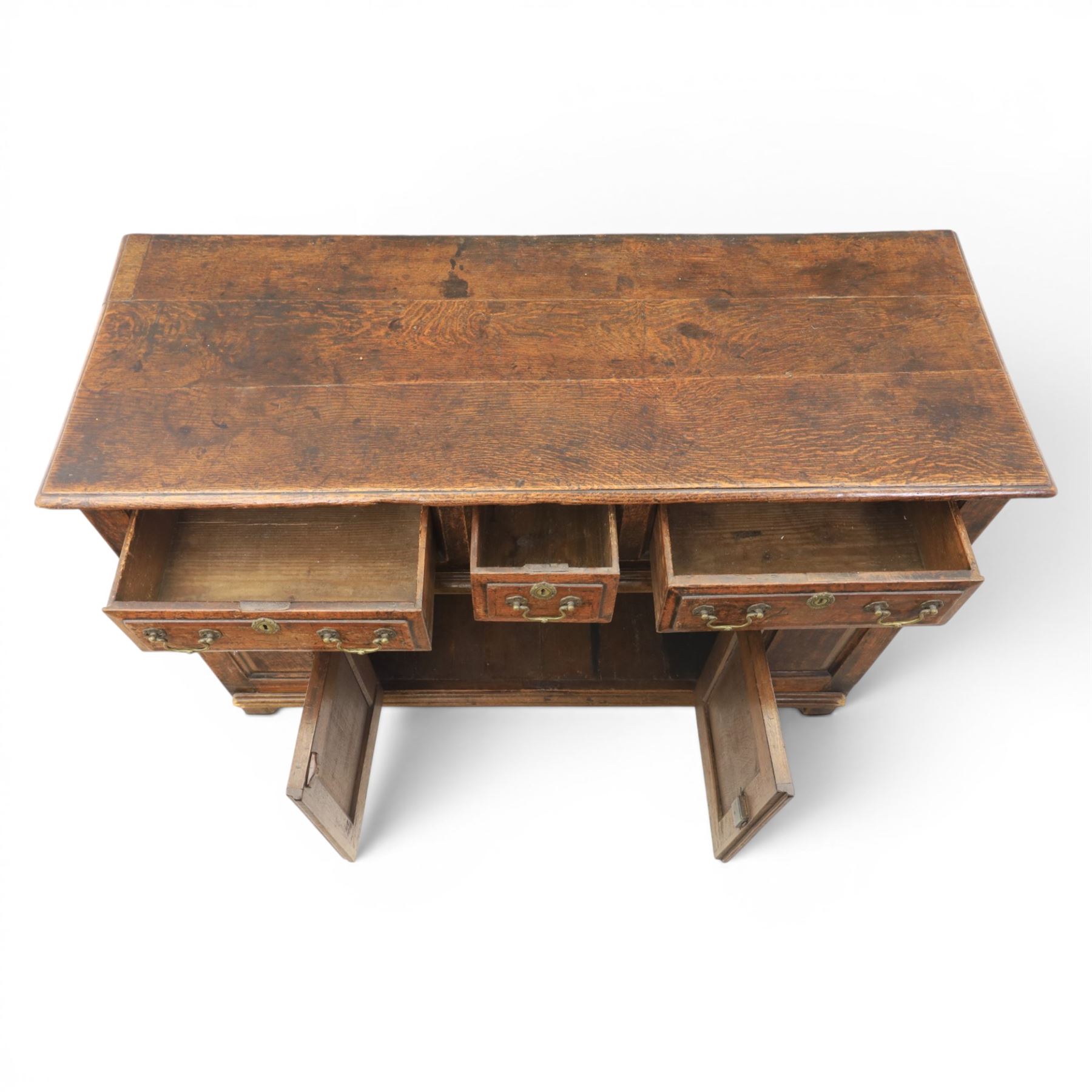 George III oak dresser base, rectangular top with moulded edge, three fielded panelled drawers with brass swan neck handles, over four fielded panelled front with the central two cupboard doors, raised on stile supports