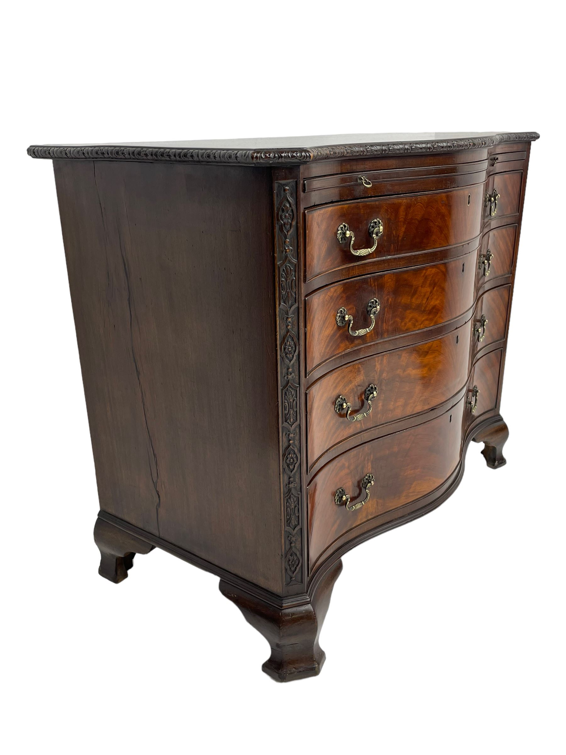Chippendale design serpentine chest, shaped moulded top carved with repeating flower head motifs, fitted with brushing slide over four graduating drawers, pierced and foliate moulded handle plates with scrolled swan neck handles, canted upright corners carved with flower heads and strapwork, on canted ogee bracket feet