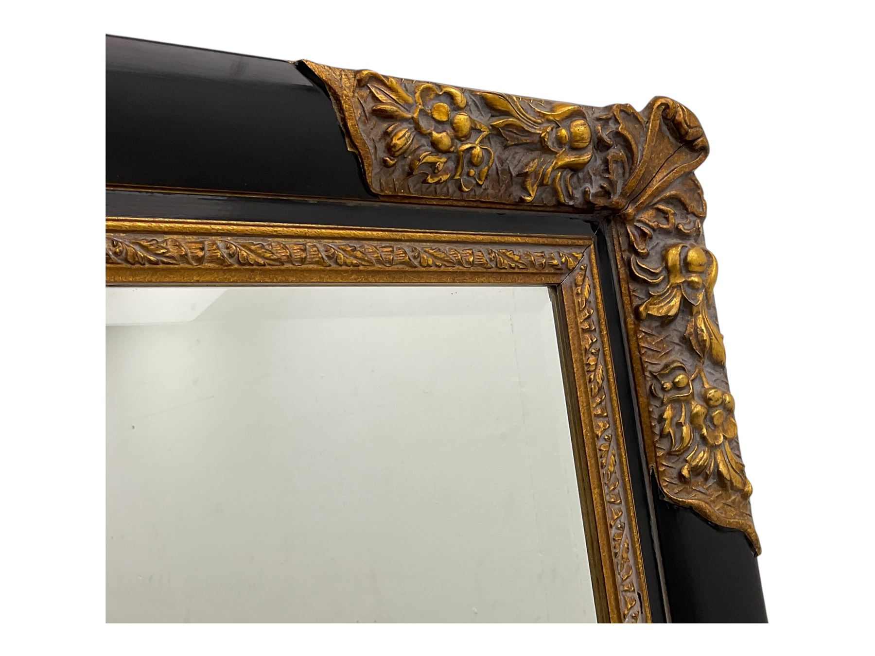 Early 20th century wall-hanging mirror, rectangular bevelled mirror plate within ebonised frame, gilt mounts to the corners carved with floral motifs 