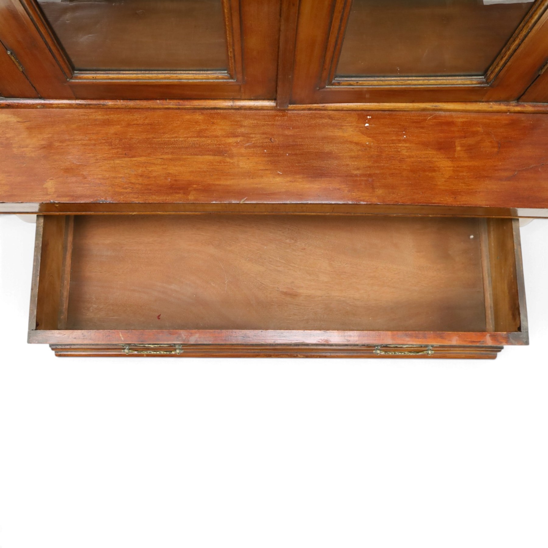 Victorian mahogany bookcase on cupboard of slender proportions, projecting cornice over dentil-frieze, fitted with twin-glazed doors enclosing three shelves, flanked by acanthus corbels, the base fitted with single frieze drawer over panelled cupboard, on skirted base