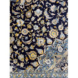 Central Persian Kashan hand-knotted carpet, the navy field with central medallion in pale blue and gold tones, surrounded by spiralling arabesques and palmettes, framed by quarter spandrels and a wide border of stylised lotus and rosette motifs between floral guard stripes, from the region of Kashan