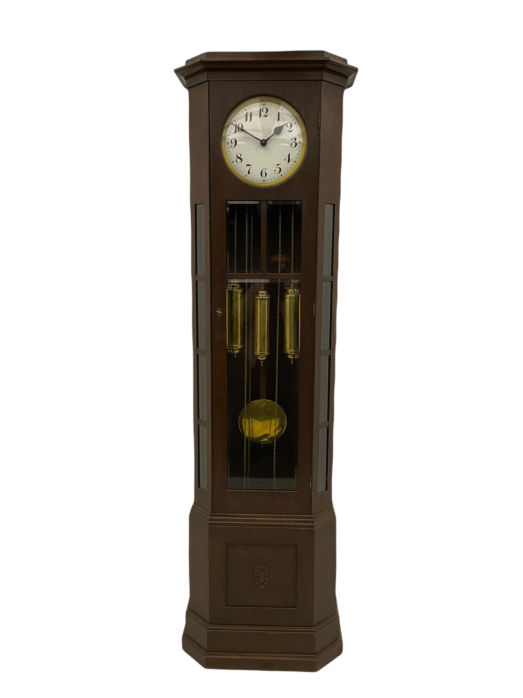 A mid-20th century weight driven floor standing clock in an oak case with canted glazed panels, full length glazed trunk door on a rectangular plinth with applied double skirting, white enamel dial with a gilt slip, upright Arabic’ numerals, minute markers, quarter hour Arabic’s and steel spade hands, with a three-train weight driven Westminster chiming movement chiming on two sets of gong rods.
With pendulum and weights.

