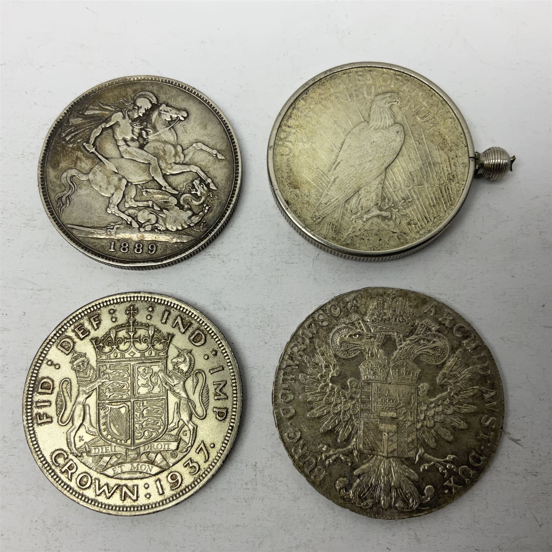 Four silver World coins comprising Queen Victoria 1889 crown, King George VI 1937 crown, Marie Thaler 1780 restrike, and mounted United States of America 1928 peace dollar 