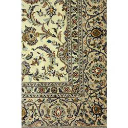Central Persian Kashan carpet, ivory ground, field with an all-over design of scrolling palmettes and floral sprays in blue and terracotta within a beige ground and pale blue floral border