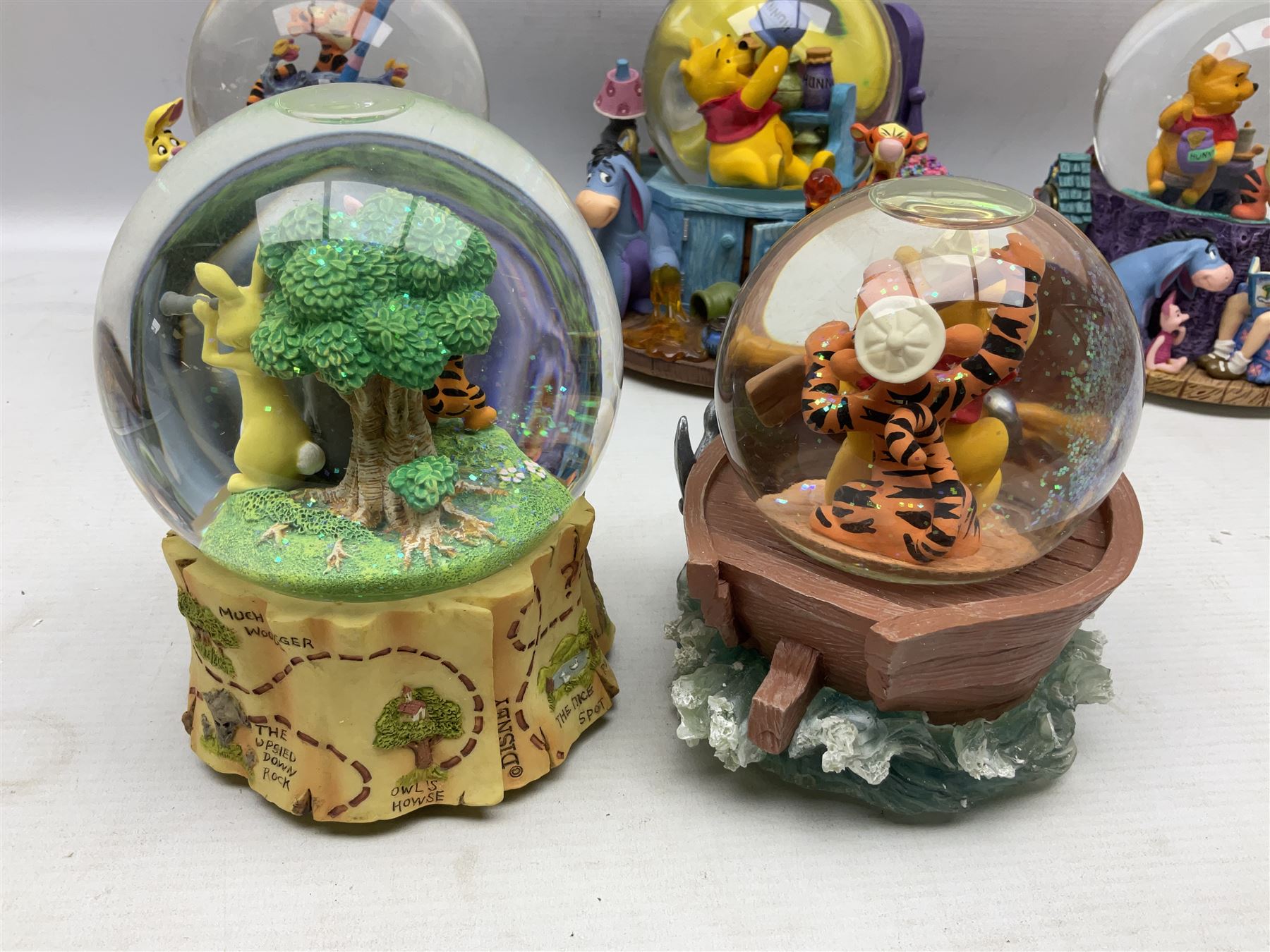 Five Disney Winnie The Pooh snow globes, to include Pooh and Piglet Sailing, Pooh's Grand Adventure and Blustery Day, together with The Walt Disney Classic Waterglobe collection globe and group Tigger, Winnie and Piglet figure under dome, all with boxes (7)