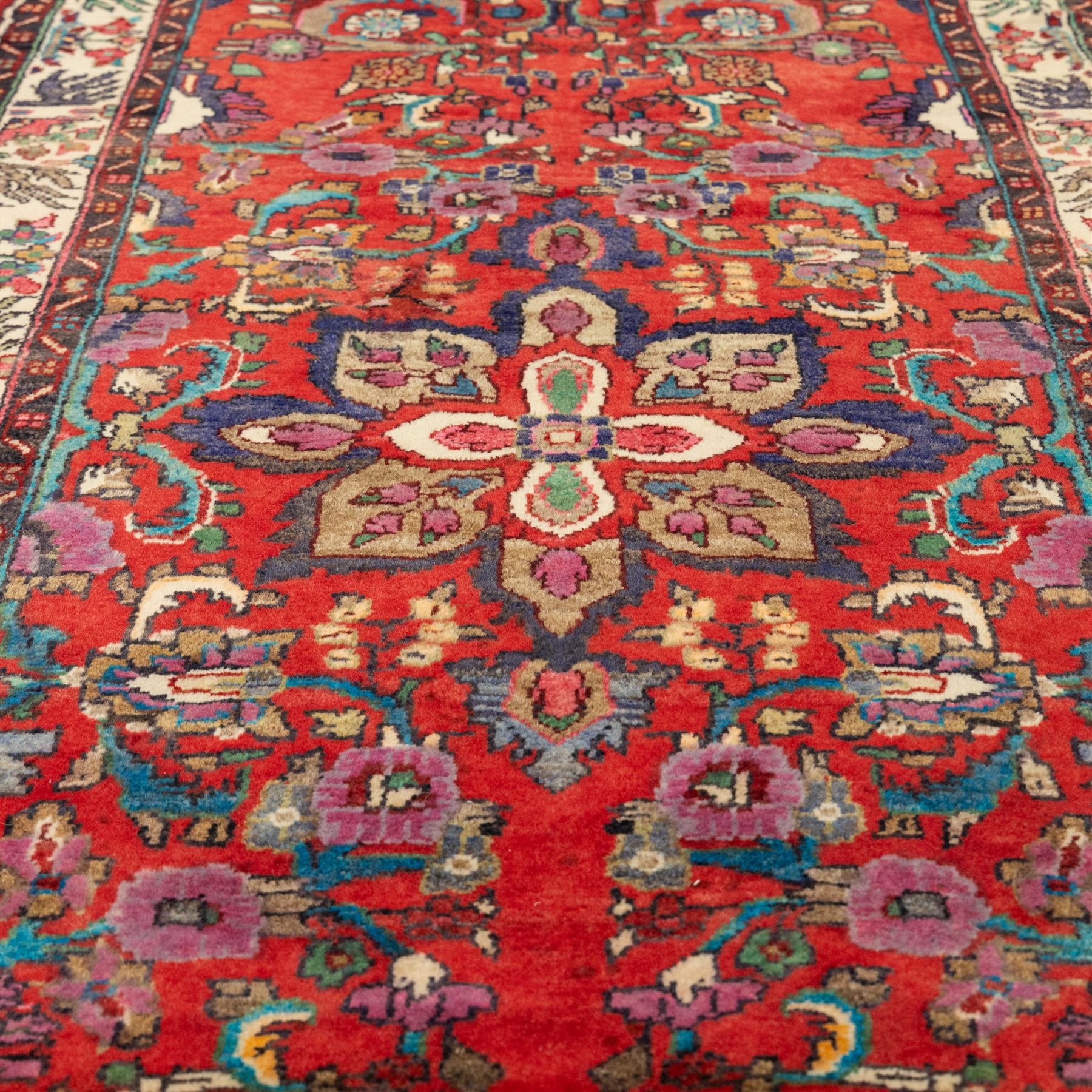 North West Persian Mahal hand-knotted runner, deep red ground, with a vertical arrangement of angular floral and geometric motifs, enclosed by an ivory border  of stylized leaves and rosettes, with guard stripes on indigo ground, cotton fringe ends 