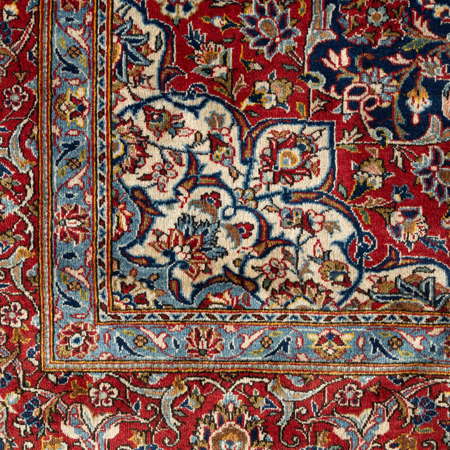 Persian Kashan carpet, navy field with central red diamond medallion enclosing floral rosette, framed by dense scrolling foliage and palmettes, triple borders in red, blue and ivory, originating from central Iran