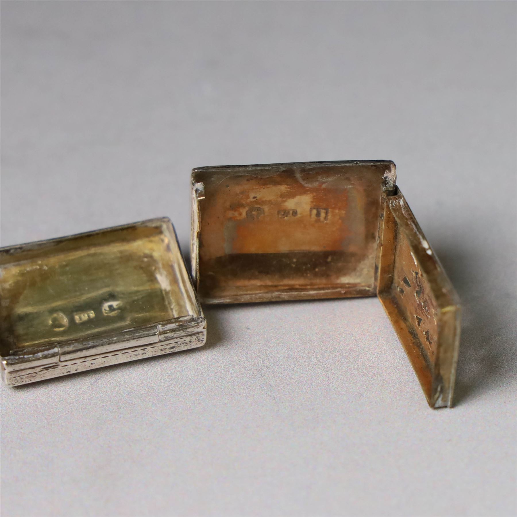 Two George III silver vinaigrettes, the first of rectangular form, the hinged cover modelled as a strap and engraved with acanthus leaves and flower heads, opening to reveal a foliate pierced gilt grille, hallmarked IT, Birmingham 1792, W2.5cm, the second of oval form, the hinged cover engraved 'C M Church' within a foliate border, opening to reveal diamond pierced gilt grille, hallmarked Cocks & Bettridge, Birmingham 1805, W2.5cm