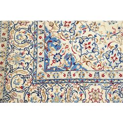 Central Persian Nain hand-knotted carpet, ivory field with central finely drawn cusped medallion of radiating palmette and arabesque form with scrolling vine work, flowering tendrils and stylized foliate motifs in a palette of pale blue, indigo, crimson and sage accents, spandrels of conforming design enclosing intricate floral sprays and arabesques within  multiple borders and narrow guard stripes, with cotton fringe ends 