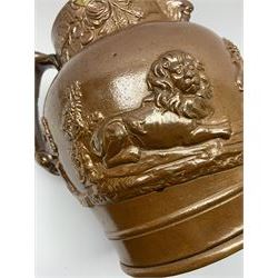 19th century salt glazed stoneware jug, with mask spout and greyhound modelled handle, the body decorated in relief with Royal Coat of Arms flanked by lions, the rim with the flowers of the union, roses, thistles and shamrocks, H26.5cm