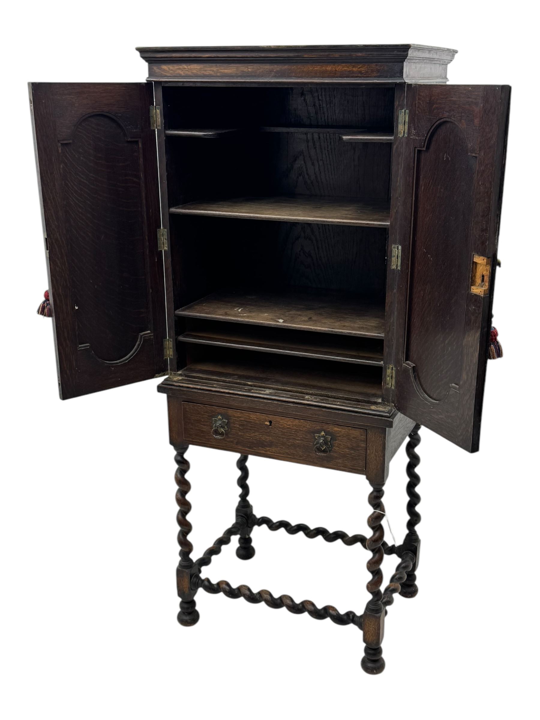 Early 20th century oak two-door cabinet, with single drawer, interior with four fixed shelves on raised barley twist stand 
 