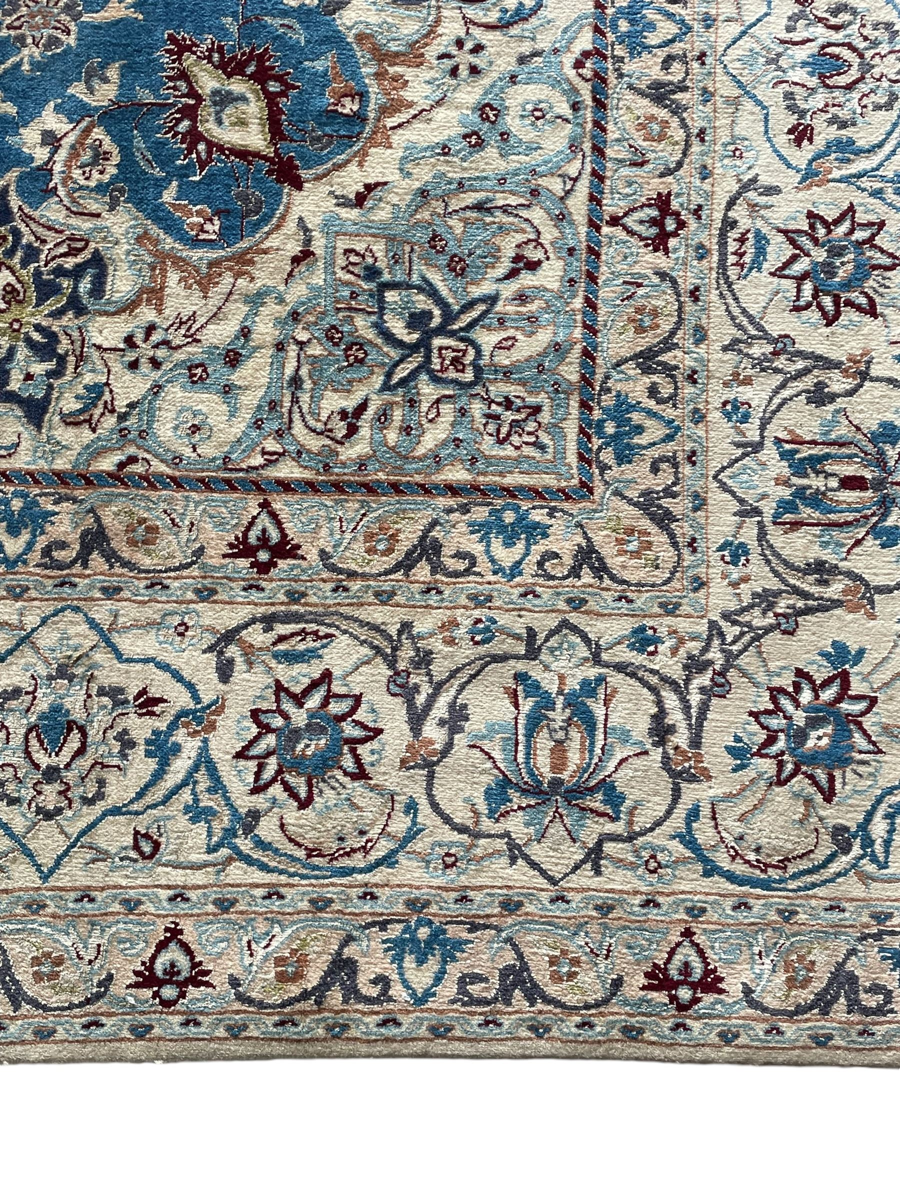 Persian Nain blue and ivory ground rug, wool with silk inlay, overall arabesque design, central medallion surrounded by interlacing and scrolled leafy branches and palmettes, the scrolling border decorated with stylised plant motifs, within guard stripes