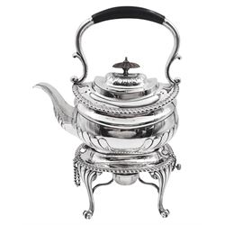 Edwardian silver spirit kettle on stand, the teapot of oval part fluted form with wooden finial, part ebonised carry handle and engraved motif to centre, upon a silver stand of oval form upon four curved and stylised pad feet, with removable silver burner, hallmarked Elkington & Co Ltd, Birmingham 1902, approximate gross weight 42.21 ozt (1313.1 grams)