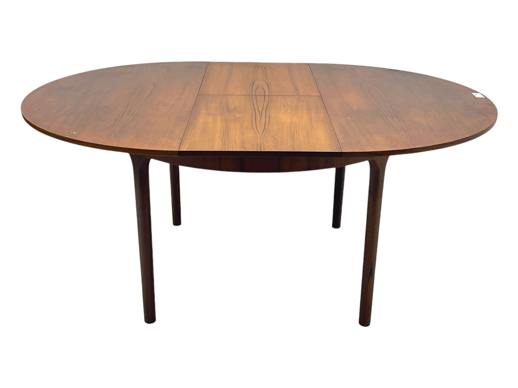 Mid-20th century teak extending dining table, circular top with pull-out extension and concealed leaf extension mechanism, on tapered supports; set of four teak dining chairs with black vinyl padded seats 