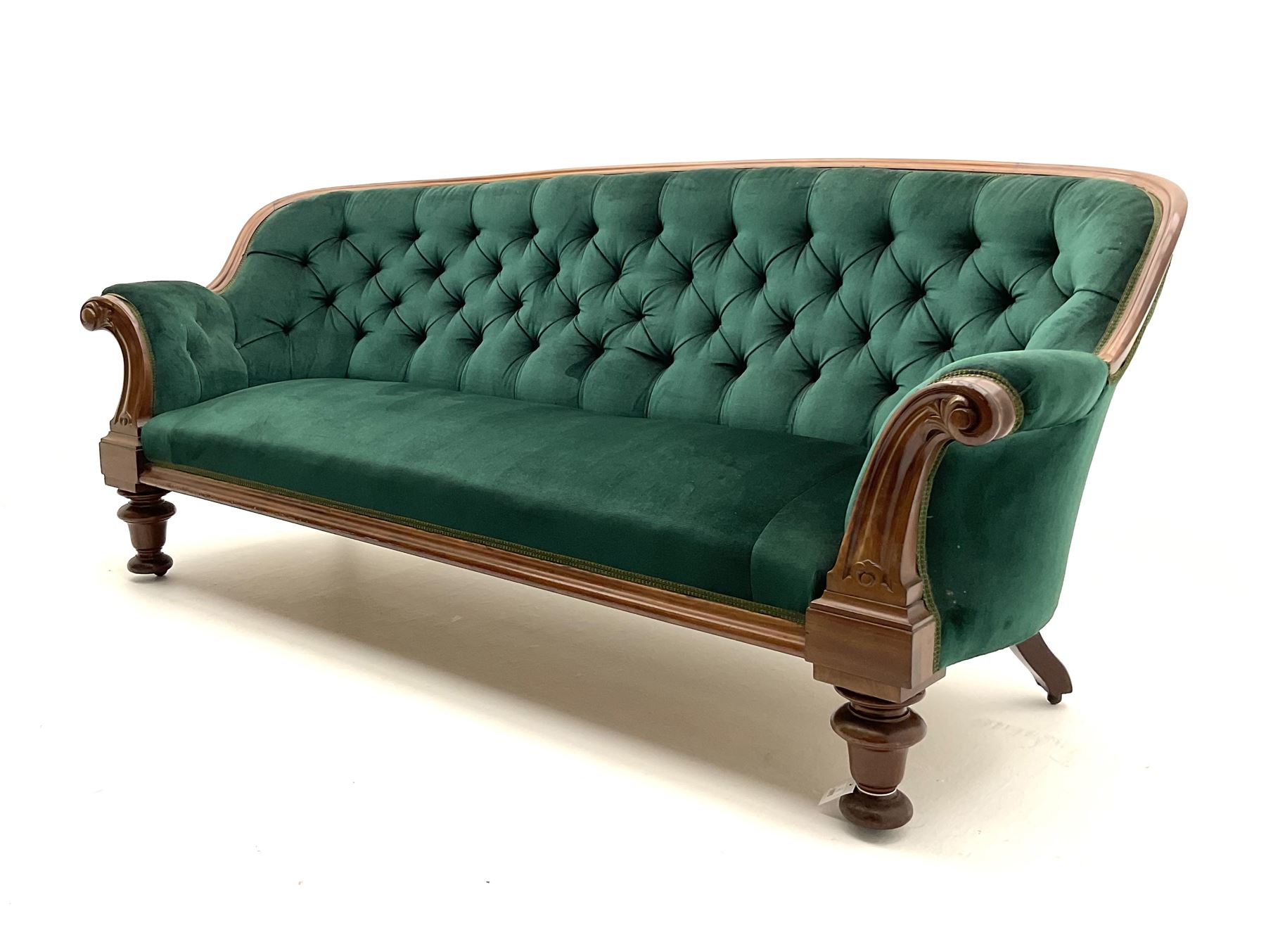 Victorian mahogany settee, upholstered in green buttoned fabric, moulded frame and scroll carved arm terminals, turned supports