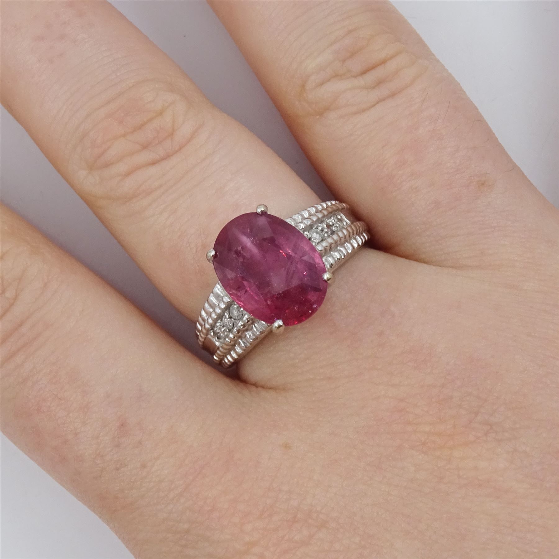 18ct white gold ruby and diamond ring, single oval cut ruby of approx 5.05 carat, with three round brilliant cut diamonds to each shoulder, Birmingham 2006