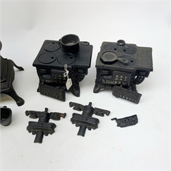 Three miniature cast iron salesman sample stoves, together with a miniature cast iron pot belly stove. 