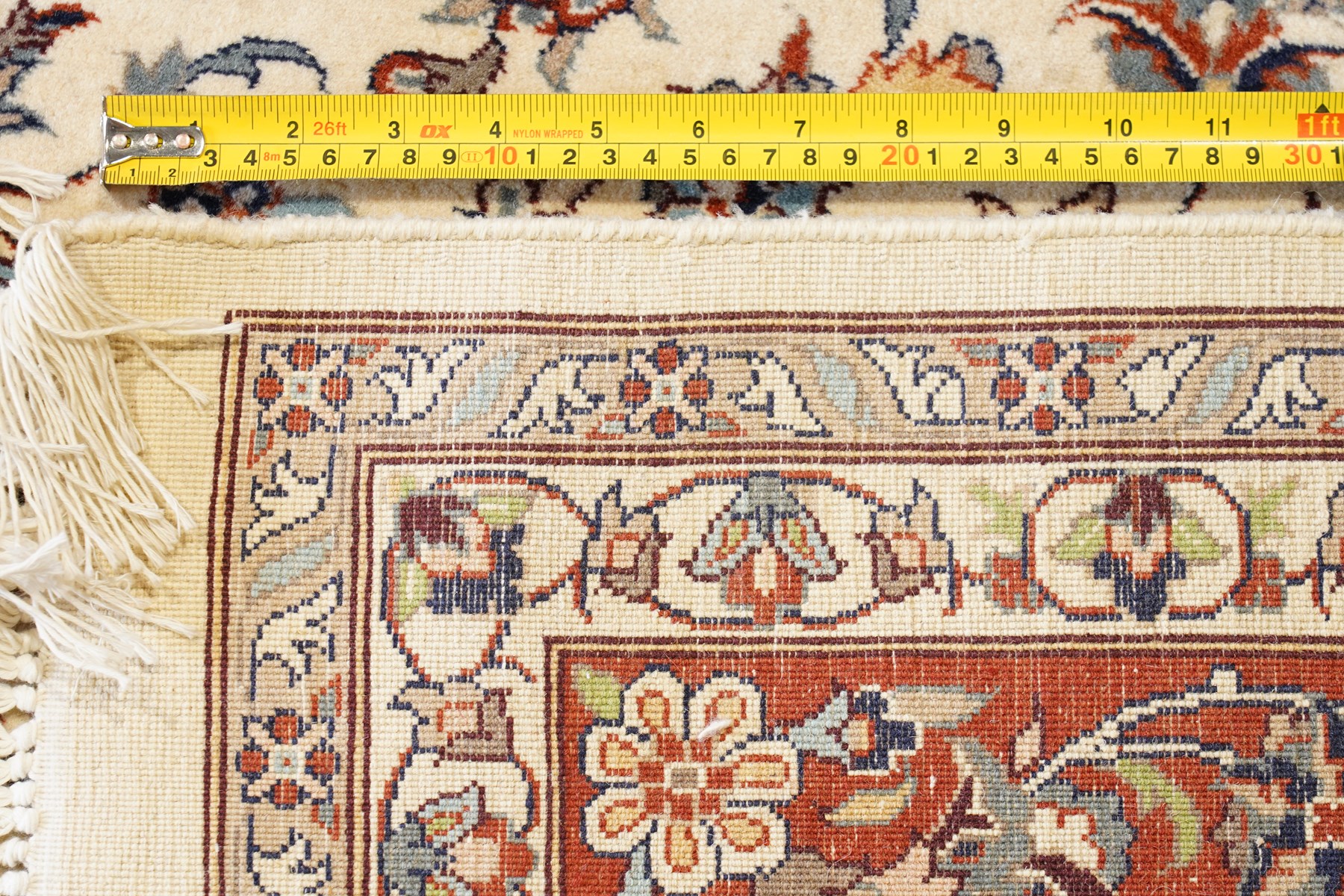 Persian ivory ground Kashan carpet, the busy field decorated with a central floral pole medallion with matching spandrels, the field profusely decorated with scrolling foliate motifs, the crimson guard stripe with repeating scrolling palmettes