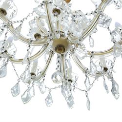 20th century Maria Theresa style twelve branch chandelier, gilt metal frame with scrolling arms clad in moulded glass, the central baluster stem issuing twelve candle sconces with glass drip pans, hung with faceted pendants and swags of cut glass beads 