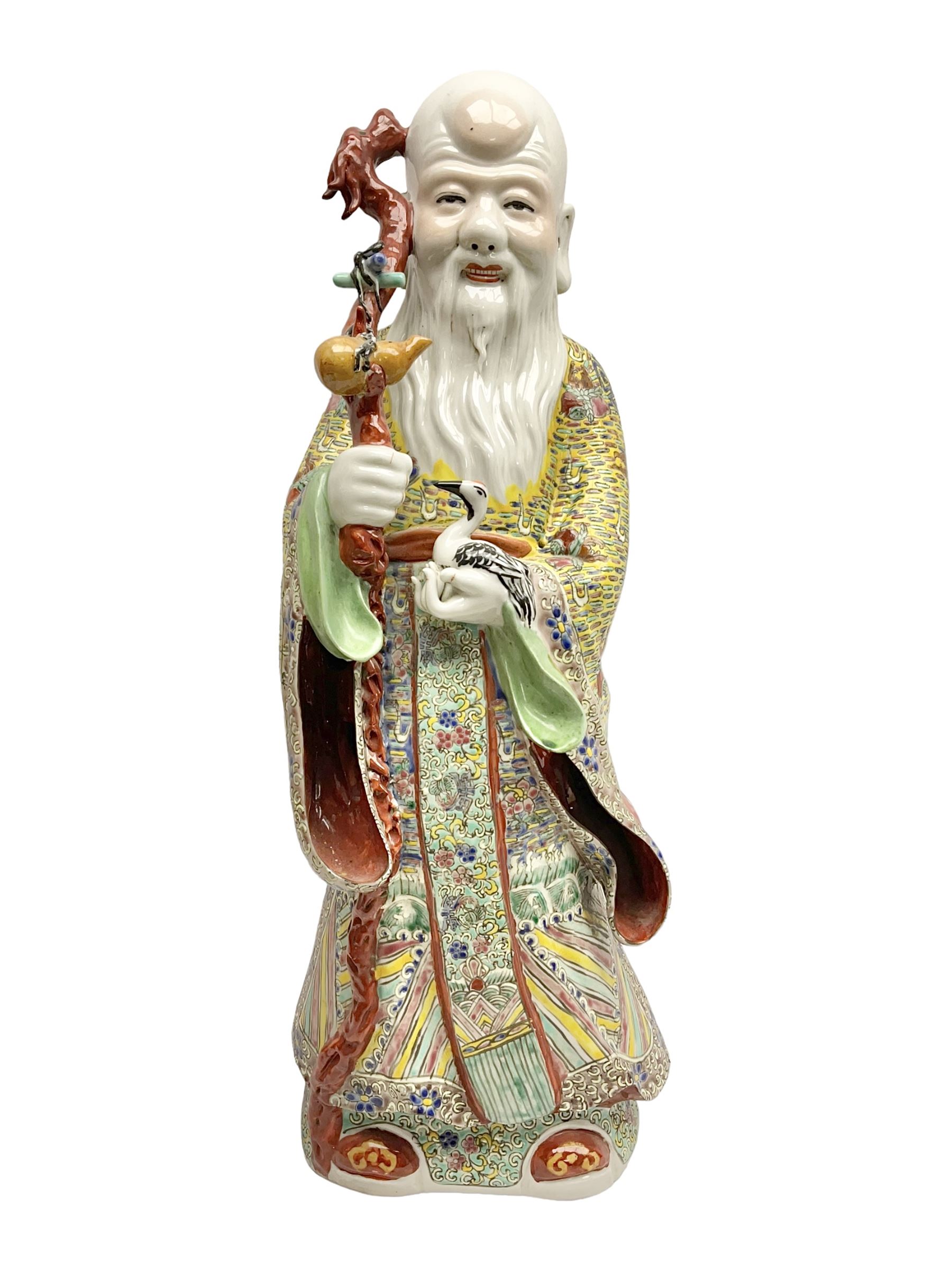 Chinese Republic Period porcelain figure, modelled as Shoulao, wearing elaborately enamelled robes decorated with peaches and flower heads, with impressed mark beneath, H55cm