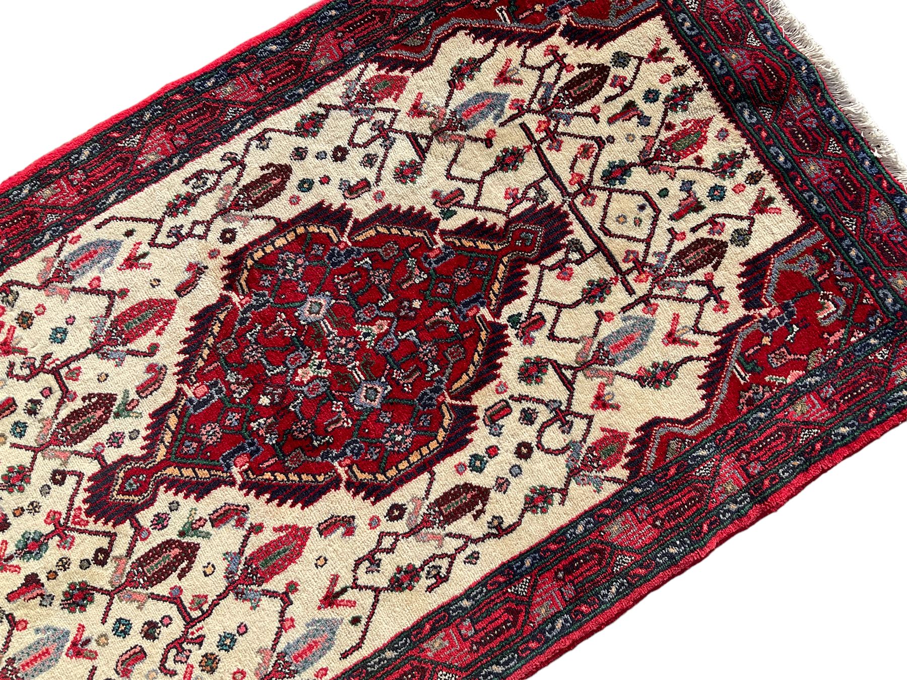 North West Persian Saveh crimson ground runner rug, the three lozenge pole medallions in an ivory field, surrounded by stylised plant motifs, the guarded border decorated with repeating geometric patterns