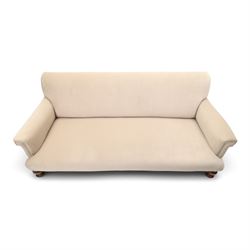 Late Victorian oak framed low three-seat settee, of traditional shape with low rolled sprung back over rolled arms and sprung seat, raised on front turned feet, upholstered in beige fabric