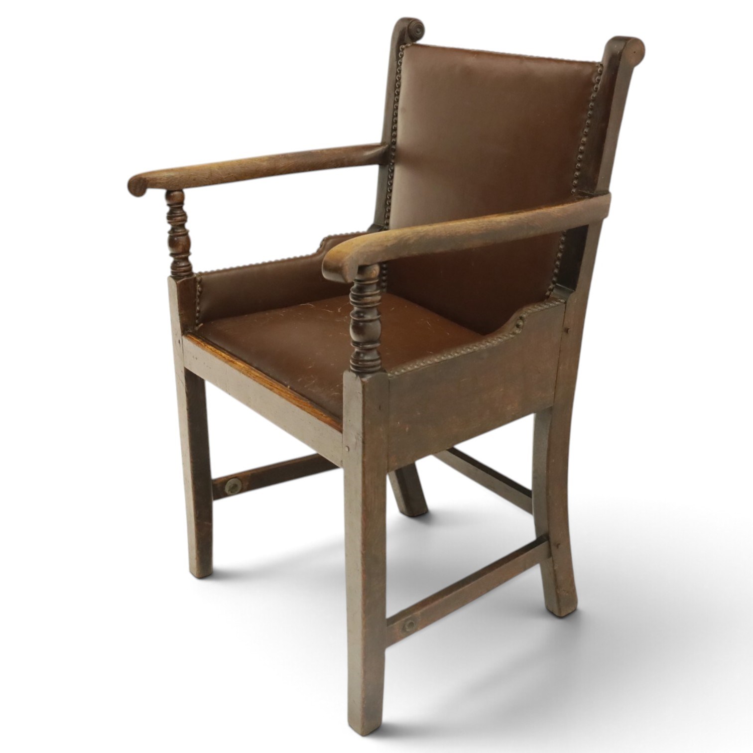 DD CL - Early 20th century oak open armchair, rectangular back with scrolled uprights, brown upholstered back and seat with brass stud edging, shaped open arms on turned supports, square legs united by stretchers