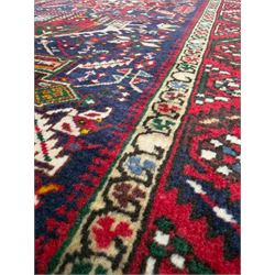 Northwestern Persian Heriz hand-knotted runner, dark indigo field with a series of linked stepped medallions in madder red, ivory, and green, flanked by angular floral motifs, within a madder red border of stylized rosettes and geometric vine motifs 405cm x 95cm