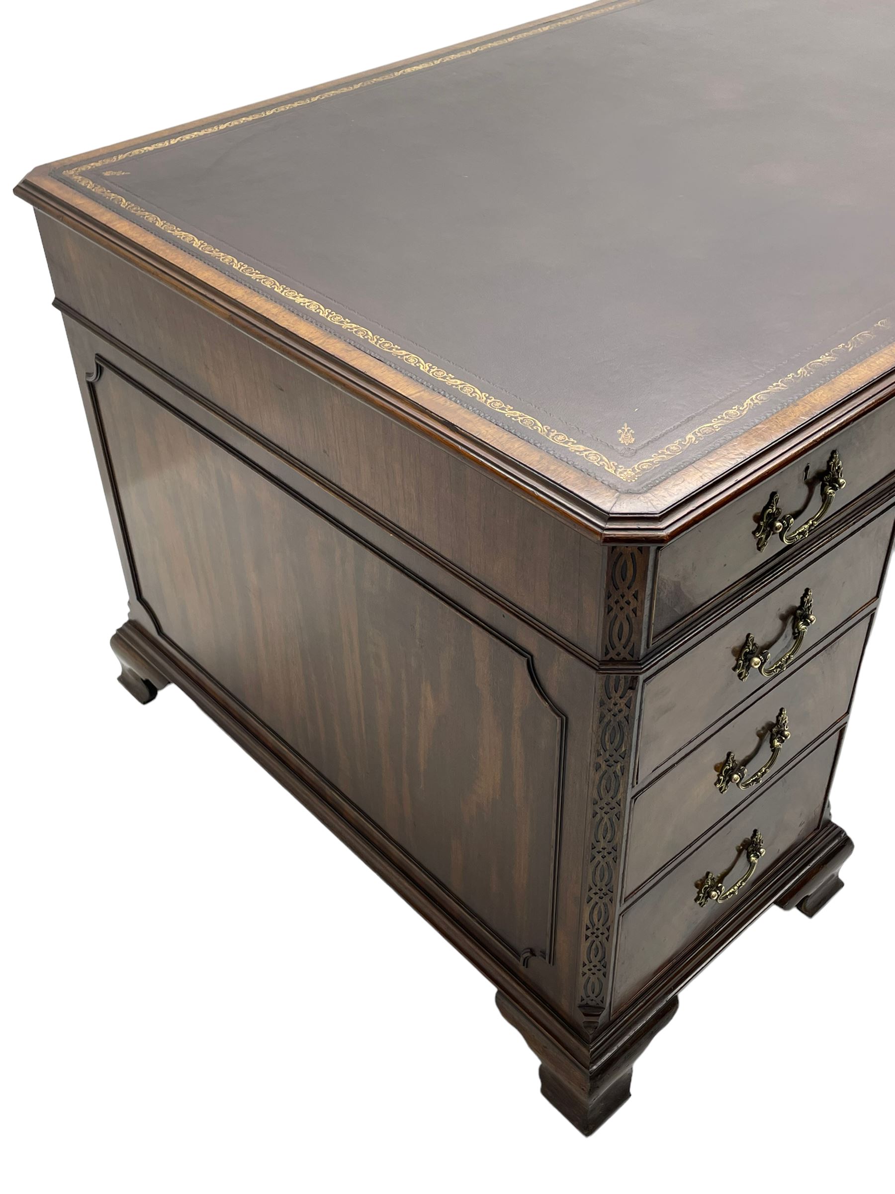 Large Georgian design mahogany twin pedestal partner's desk, moulded rectangular top with canted corners and inset leather writing surface, fitted with nine drawers and two cupboards, the pedestals with canted uprights decorated with blind fretwork, on ogee bracket feet