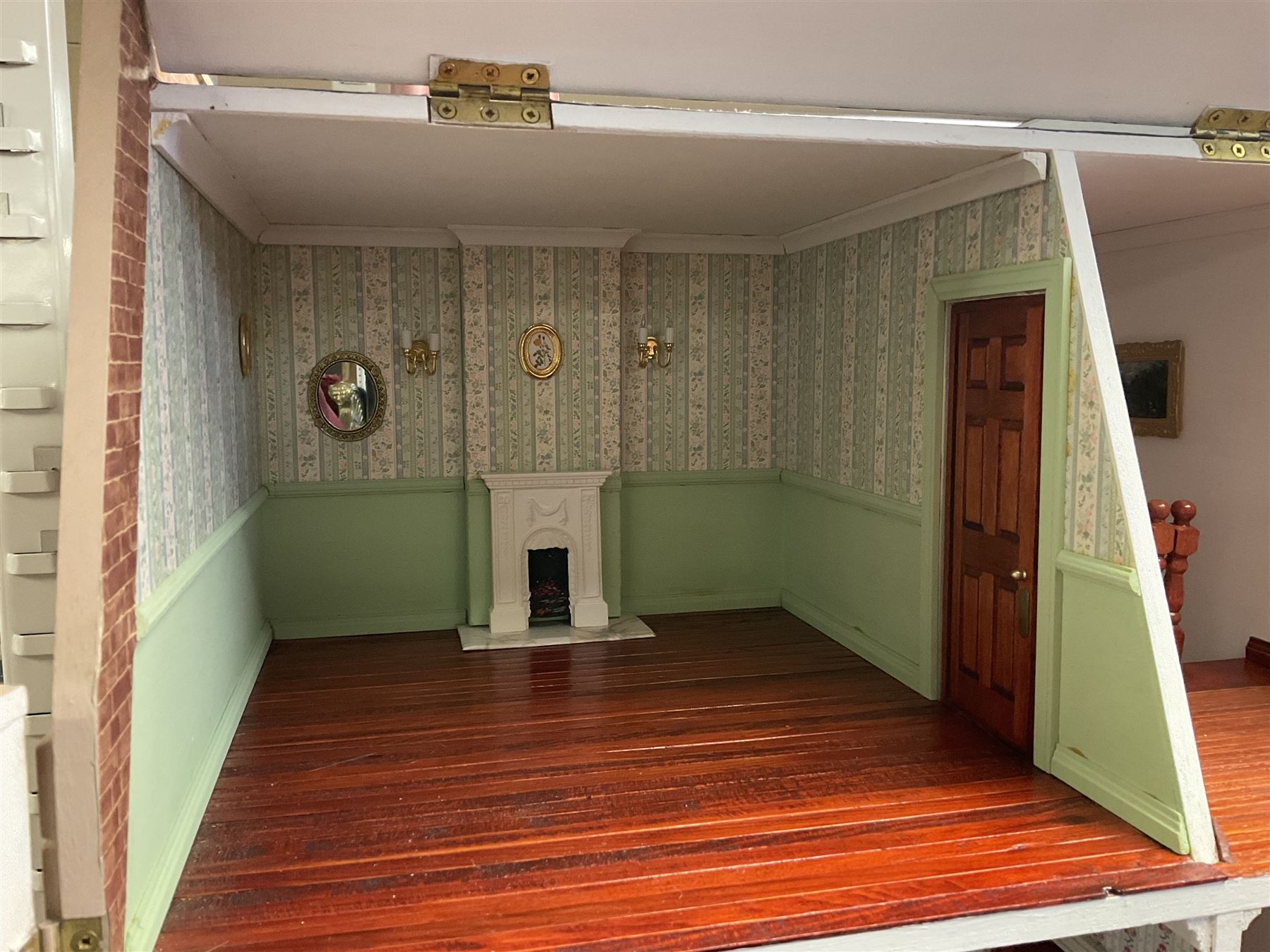 'The Hollies' - good quality sectional wooden doll's house in the form of a Georgian style four-storey bay windowed town house with simulated brick front elevation, rendered sides, off-set corner stonework, faux slate-hung top floor with flat roof and chimney stack, working sash windows, iron railings around front basement courtyard with hinged front elevation to two rooms with  spiral staircase, side hinged central section approached by external steps with iron balustrades to the sides leading to a front door, entrance hall with stairs to landing and two rooms on two floors with dado panelling and fire-surrounds, the top floor with top hung front elevation revealing stairs to a landing and bedroom; wired for electricity L51cm D65cm H107cm including chimney; together with a good quantity of quality wooden furniture and accessories including piano, dressers, bookcase and books, rugs, double half-tester bed, metalware, pictures etc