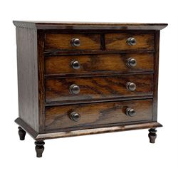 Miniature oak chest, rectangular top over two short and three long graduating drawers, turned feet