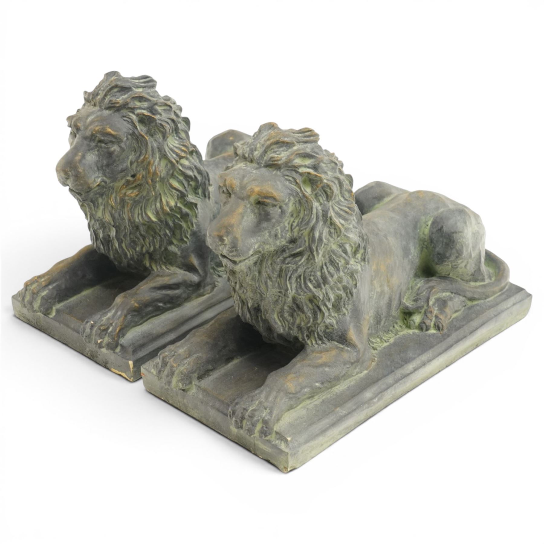 Pair of bronze-effect composition stone recumbent lions, with verdigris-style weathered finish, each raised on rectangular plinth base