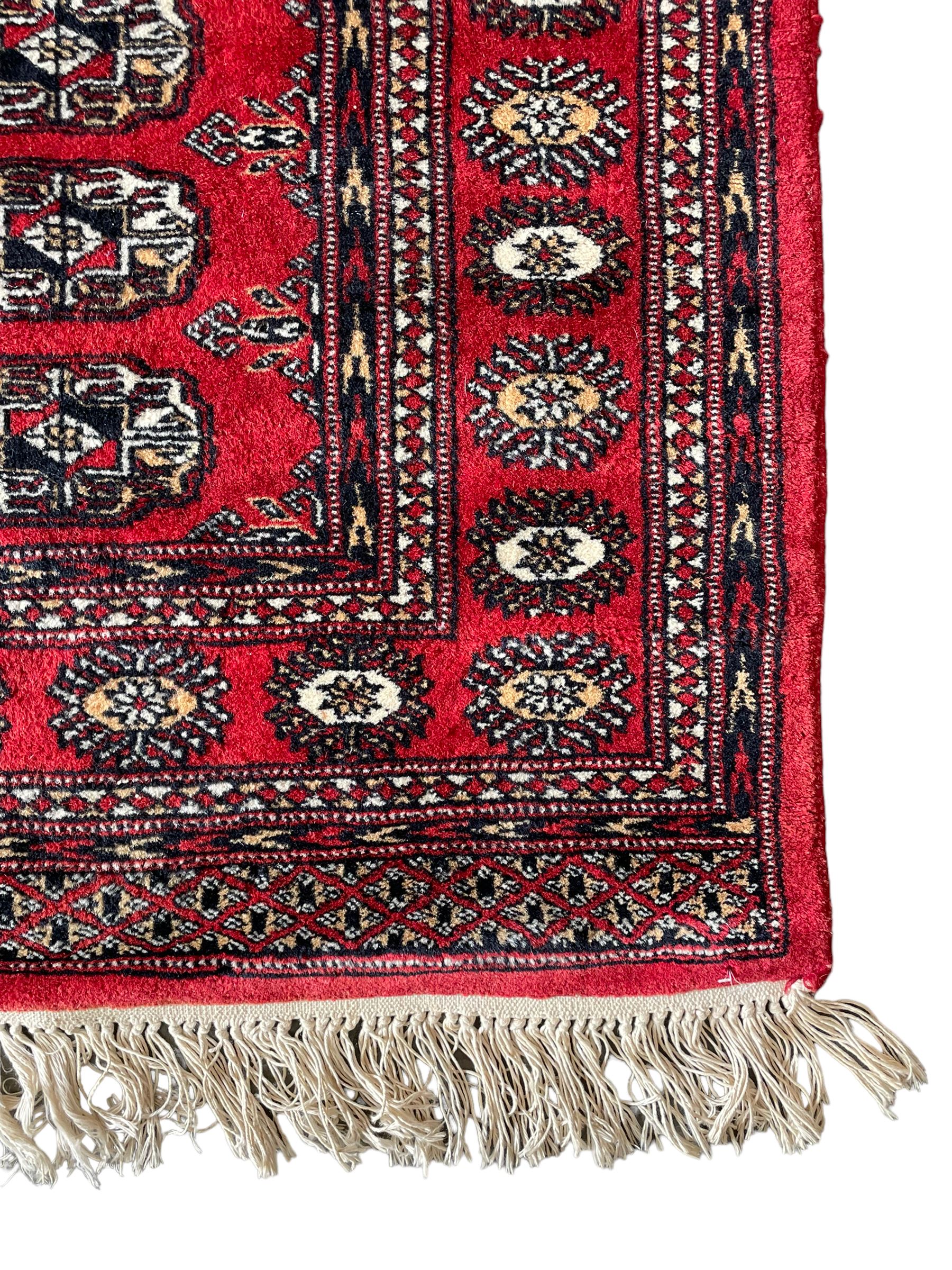 Tekke Bokhara red ground rug, decorated with two rows on Gul motifs, geometric design borders decorated with stylised floral motifs 