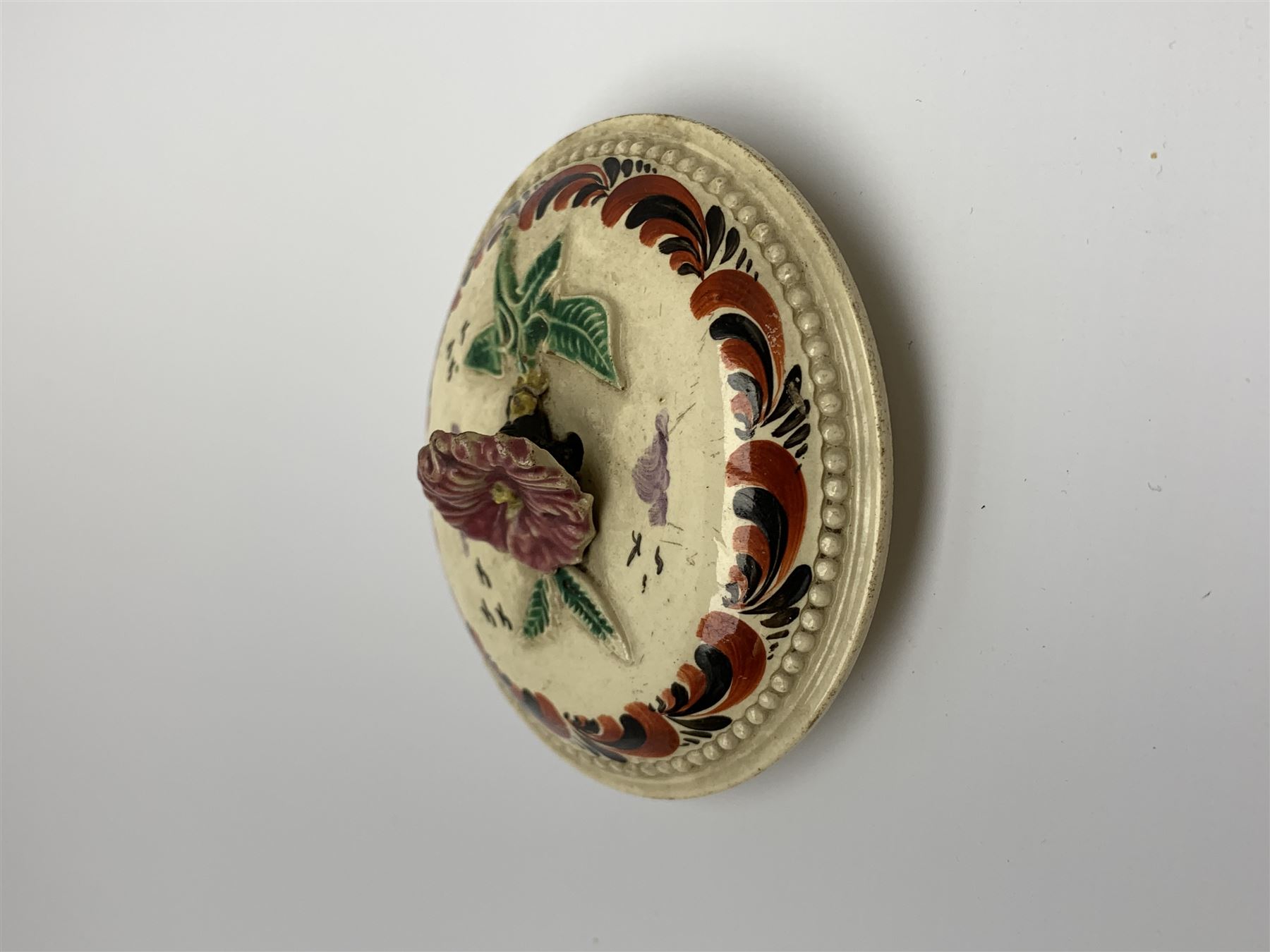 18th century creamware teapot, probably Leeds, with reeded entwined handle and floral finial to the cover, the body with hand painted polychrome decoration of figure to one side, and floral spray to the other, collectors paper label beneath inscribed Leeds Pottery, H11.5cm