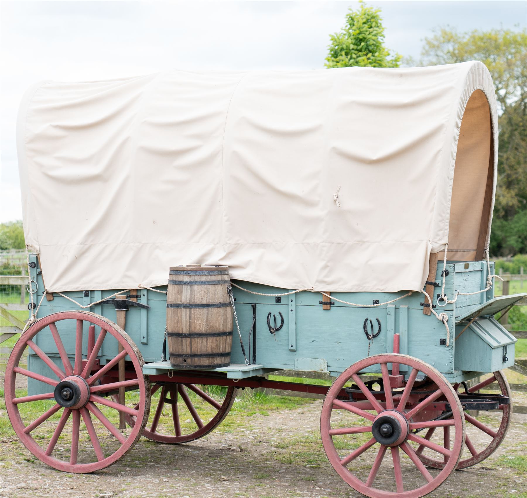 Western Covered Chuck Wagon

A large four wheeled covered wagon of timber construction, painted pale green with red painted wooden spoked wheels and a cream canvas tilt over an arched frame. The wagon has a traditional box body with covered rear compartment, front driving position, underbody turntable steering and iron fittings throughout. Fitted with external equipment details including a side mounted barrel, lidded storage chest, rope tie downs, horseshoe fittings and rear storage box.

Features

• Pale green painted timber body
• Cream canvas tilt over arched frame
• Covered rear compartment
• Front driving position
• Side mounted barrel
• External lidded storage chest
• Rear storage box
• Wooden spoked wheels
• Iron tyres
• Underbody turntable steering
• Rope tie downs
• Horseshoe fittings
• Iron hardware and brackets
• Brass restoration plaque to rear

Dimensions:
Overall length: 335 cm
Width: 170 cm
Height: 275 cm

Wheel Diameters:
Front wheels: 92 cm
Rear wheels: 112 cm

Seating:
Driver: 1
Passenger: Rear covered compartment