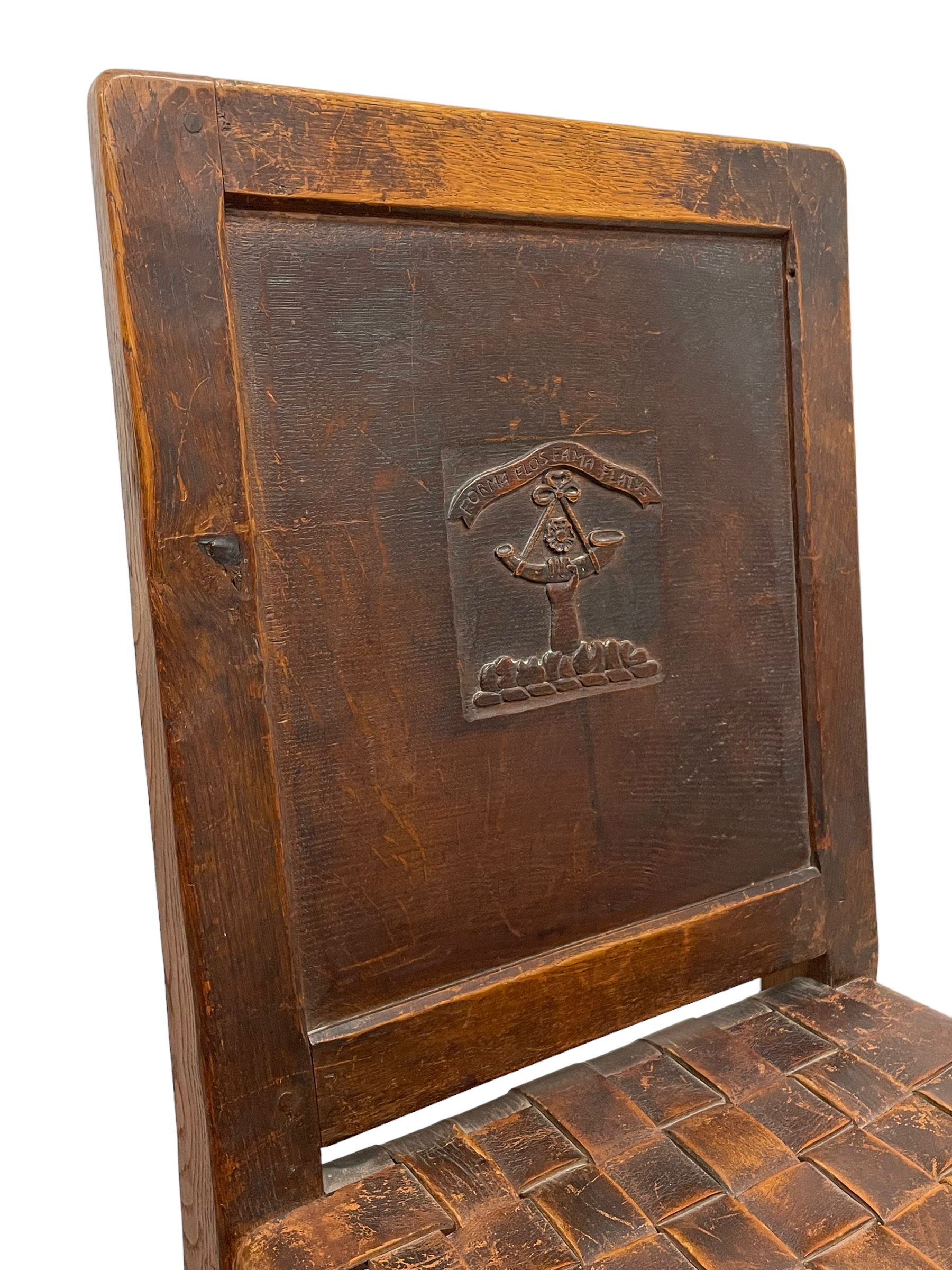 Mouseman - circa. 1930s set of six (4+2) oak dining chairs, panelled back carved with the Bagshawe family crest, the moto 'Forma Flos Fama Flatus' over an arm grasping a bugle-horn with ribbon tie and Yorkshire rose motif, adzed frame, leather lattice strap seat, on octagonal supports united by stretchers, two carvers and four side chairs, each carved with mouse signature, by Robert Thompson of Kilburn 

Provenance: Owned since manufacture by the Bagshawe family, descendants of the Staithes Group Artist Joseph Richard Bagshawe RBA (1870-1909).