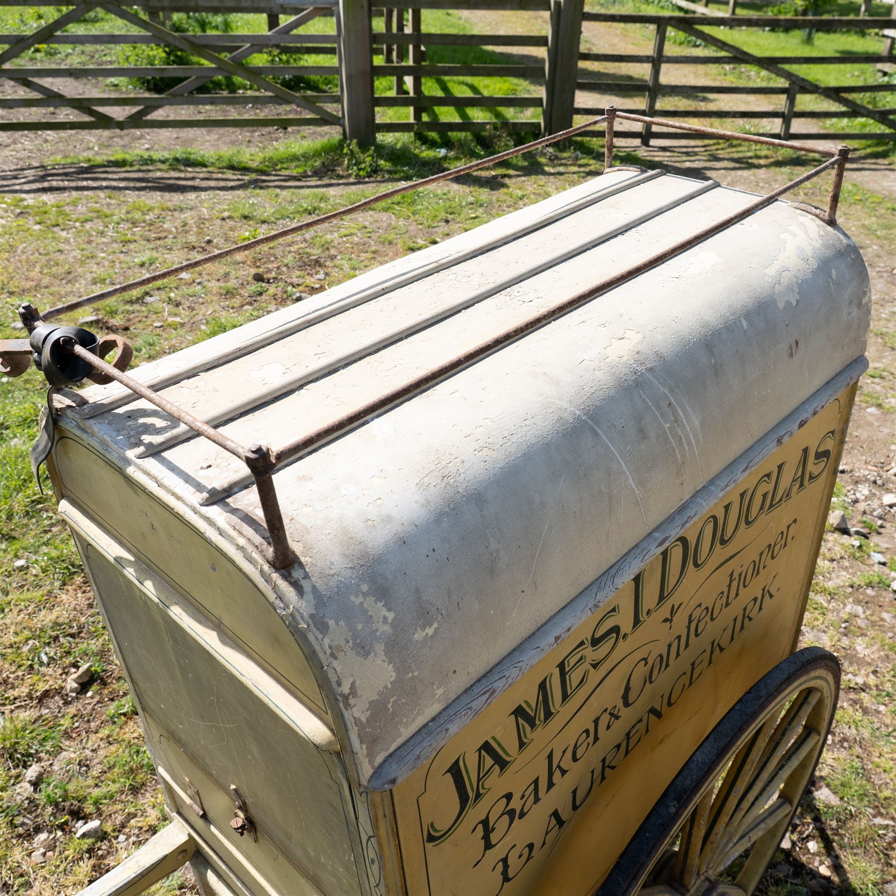 James I. Douglas, Baker & Confectioner, Laurencekirk Hand Drawn Delivery Cart

An attractive late 19th or early 20th century hand drawn baker's delivery cart, finished in cream and retaining its original hand painted advertising livery for James I. Douglas, Baker & Confectioner, Laurencekirk. The enclosed body features a curved roof with external luggage rail, rear access doors and internal shelving for the transport and delivery of bread, cakes and confectionery. Mounted on large wooden spoked wheels with iron tyres and fitted with shaped shafts for a single horse, this is a highly decorative and increasingly scarce example of a provincial tradesman's delivery vehicle, offering excellent display potential for collectors, museums, period interiors or commercial settings.

Features:
• Original hand painted signwriting for James I. Douglas, Baker & Confectioner, Laurencekirk
• Enclosed delivery body with curved roof and external luggage rail
• Rear opening access doors with internal storage compartments
• Original internal wooden shelving and racks
• Large wooden spoked wheels with iron tyres
• Shaped shafts for single horse traction
• Builder's mark for Geo. Roberson Ltd., Wallington
• Decorative cream painted finish with period lining and detailing
• Suitable as a display piece, museum exhibit or advertising feature

Dimensions:
Overall length: 170 cm
Body length: 104 cm
Width: 83 cm
Height: 150 cm

Wheel Diameter:
Wheels: 95 cm