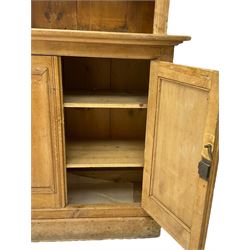 Late 19th century stripped pine dresser, shaped sloping pediment over two glazed doors, rectangular top over double panelled cupboard, on plinth base