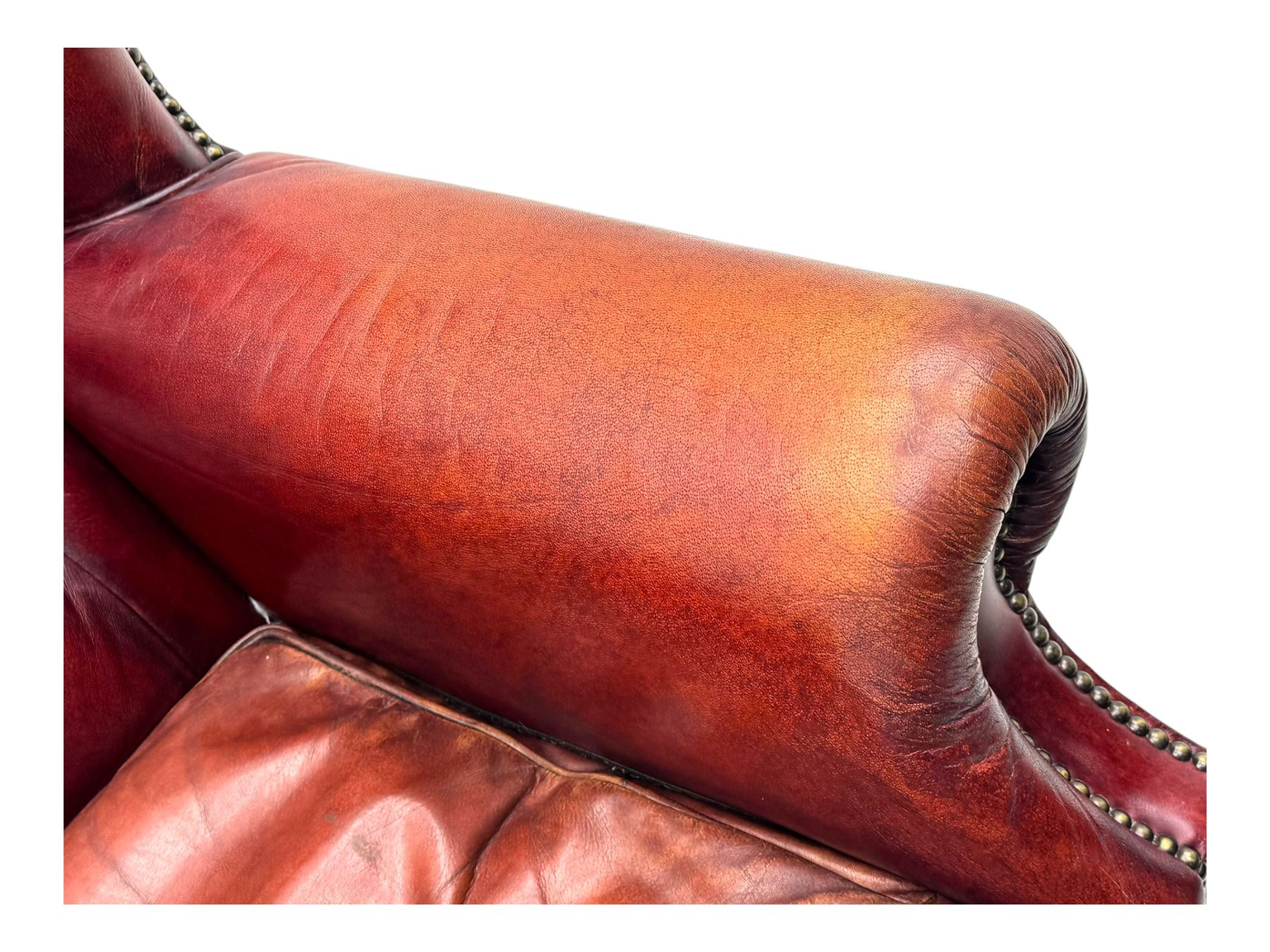 Tetrad - pair of 'Oskar' wingback armchairs, deep-buttoned oxblood leather upholstery with rolled arms and brass stud trim, raised on turned and reed moulded feet