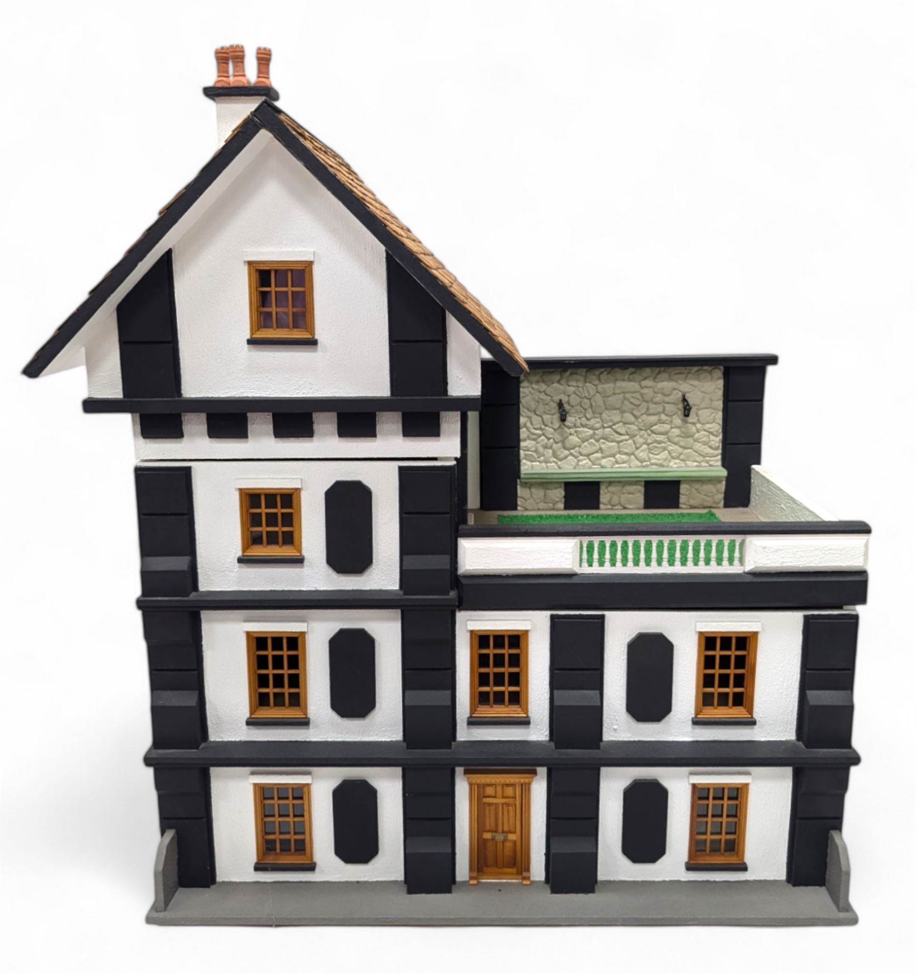 1:24 scale four-storey tudor-style dolls house, with black and white exterior, balcony garden, glazed panelled windows and wooden shingle roof, with decorated interior and wired fireplaces and lighting, H65cm, W58cm, D31cm, 