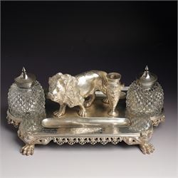 19th century Walker & Hall, silver plated inkstand, oblong and on four paw feet, the border decorated with pierced shell design, each side with a pen-rest, with two cut-glass bottles and central lion and urn finials, engraved to the front with an inscription, H15cm, L30cm