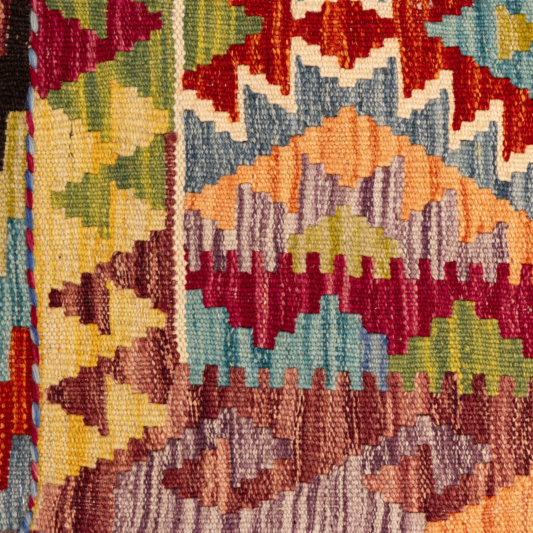 Afghan Chobi flatweave kilim, with a repeating stepped diamond medallion design in ivory, green, rust, teal, purple, indigo, and framed by chevron and geometric borders