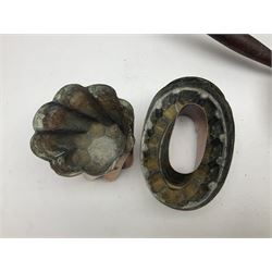 Four Victorian copper moulds, together with a graduating set of copper pans with wooden handles and finials to covers, largest pan 