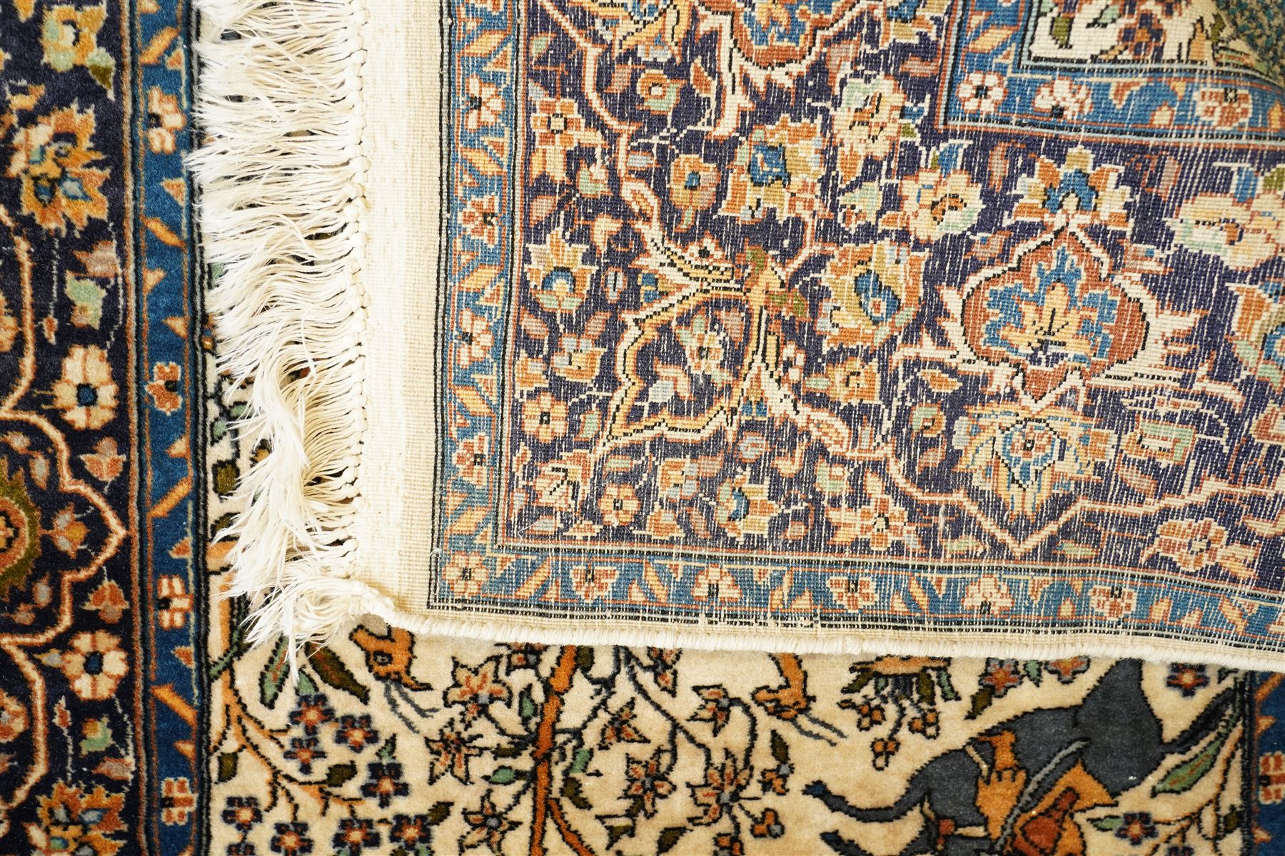 Persian pictorial rug featuring a hunting scene, ivory field with mounted hunters, animals, birds and trees, rich navy and terracotta floral border with rosettes and palmettes 